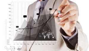 Businessperson drawing a rising chart with a marker, symbolizing growth.