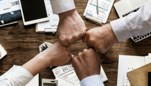 Close-up of hands forming a fist bump over a desk with business documents.
