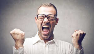 Excited man in glasses celebrating a win, showing enthusiasm and success.