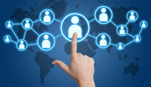 Hand pointing at a connected network of icons over a world map, representing global connections.