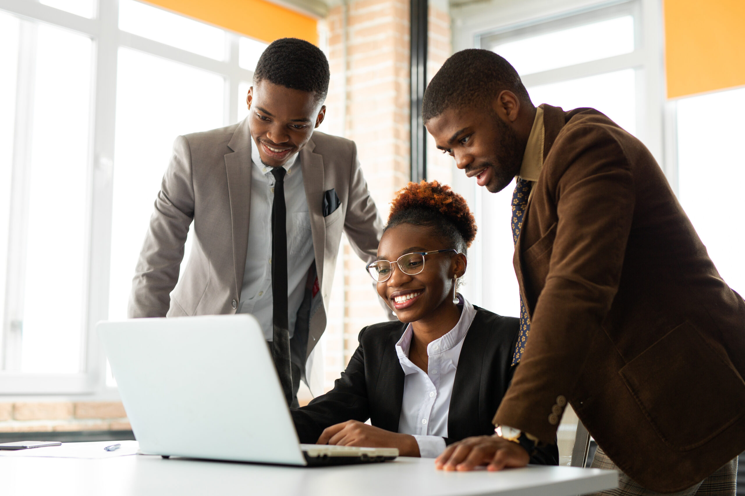 Three professionals reviewing data on a laptop in a modern office.