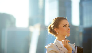 Businesswoman with a pen, looking thoughtfully at a cityscape.